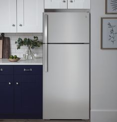 a silver refrigerator freezer sitting in a kitchen next to white cabinets and blue drawers