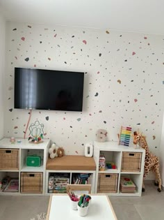 a television mounted on the wall in a child's room with toy bins