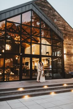 a bride and groom standing in front of a large glass building with stairs leading up to it