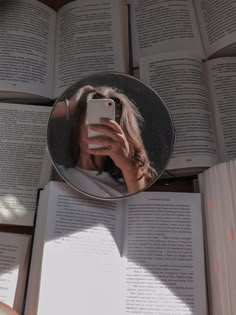 a woman taking a selfie in front of an open book with her cell phone