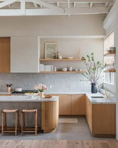 an open kitchen with wooden cabinets and counter tops, along with two stools in front of the island