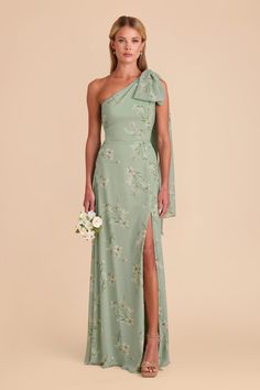 a woman in a green dress with flowers on the side and one leg slited