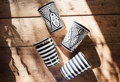 three black and white striped cups sitting on top of a wooden table next to each other