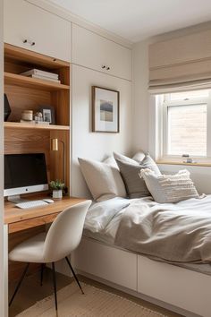 a bed sitting under a window next to a desk with a computer on top of it