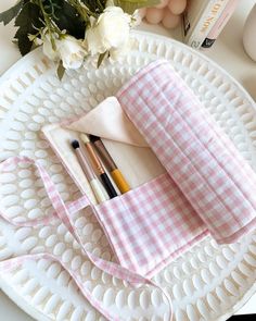 a white plate topped with pink and white checkered napkins next to two pens