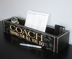 a desk with a pen, watch and notepad on it that says coach thanks for all you do