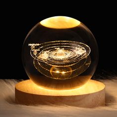 a glass ball sitting on top of a wooden stand next to a black background with an image of the solar system in it