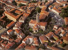 an aerial view of a city with lots of red roofs and tall buildings in the background