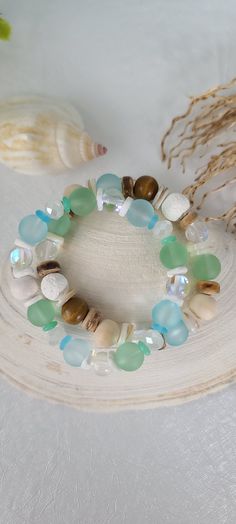 TitiTataStore.com Always FREE SHIPPING and a FREE GIFT! I Will Ship Within 24 Hours! Description: A Set of Two Summer Style Handmade Beach Bracelets.   Materials: 10mm Natural Wood Beads, 10mm Frosted Seafoam Green Sea Glass Beads, 10mm Frosted Ocean Blue Sea Glass Beads, 8mm Clear/Matte Mystic Aura Quartz Beads, 10mm Lava Rock Beads, 10mm Heishi Natural Seashells, 6mm Green/Blue Sea Glass Heishi Beads, 6mm White Seashells Heishi Beads, 8mm Faceted Glass Rondelle Beads, and 8mm Coconut Heishi Beads.  A high-quality elastic stretch cord is used to string the beads for durability. Size: Each bracelet is suitable for a wrist circumference of about 7". Final Touch: Your bracelet will be nicely packed in a Burlap Gift Bag. ❤ All orders are shipped FREE via USPS First Class Mail with tracking nu Green Hand Wrapped Wrap Bracelet For Beach, Green Stackable Stretch Bracelet For Beach, Handmade Strand Stretch Bracelet For Beach, Green Wrap Bracelet With Round Beads For Beach, Bohemian Stackable Stretch Bracelet For Beach, Bohemian Stackable Wrap Bracelet For Beach, Adjustable Stackable Stretch Bracelet For Beach, Green Hand Wrapped Friendship Bracelets For Beach, Green Stackable Jewelry For The Beach