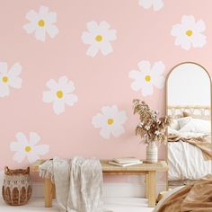 a pink bedroom with white flowers painted on the wall and a mirror in the corner