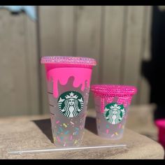 two starbucks cups with sprinkles on them are sitting on a table next to each other