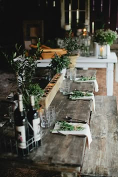 a long wooden table topped with lots of plates and glasses filled with food next to bottles of wine