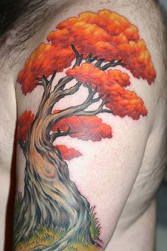 a man's arm with an orange tree tattoo on the back of his shoulder