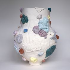 a large white vase with many different colored objects on it's side and sides