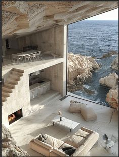 a living room with a fire place next to the ocean and stairs leading up to it