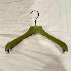 a green coat hanger with the word gucci on it and a black hook