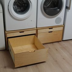 two washers sitting next to each other on top of a wooden drawer in front of a dryer