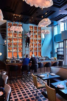 people sitting at tables in a restaurant with lots of bottles on the shelves behind them