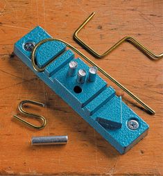 a blue piece of metal sitting on top of a wooden table next to some hooks