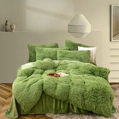 a bed covered in green fluffy blankets and pillows