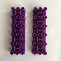 two pieces of purple plastic sitting next to each other on a white surface with holes in the middle