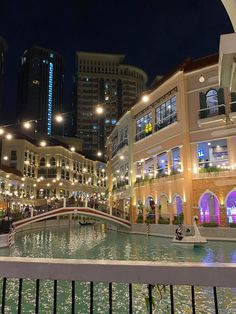 the city is lit up at night and there are people walking around in the mall