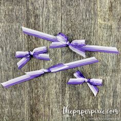 three purple and white bows tied on wooden boards