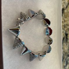 a bracelet with silver and red glass beads on top of white marbled paper in a box