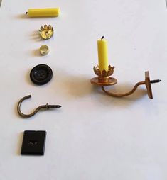 a candle is sitting on a table next to other items that include screwdrivers, an eyeglasses and a lighter