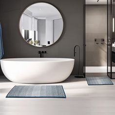 a white bath tub sitting under a round mirror