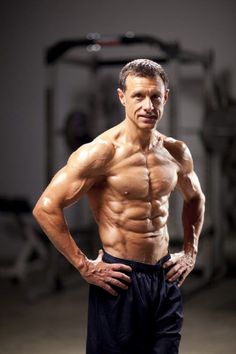 a man standing in front of a gym machine with his hands on his hips and looking at the camera