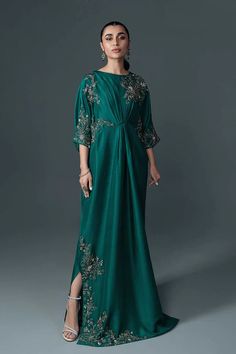 a woman in a long green dress with an open back and floral embroidery on the side