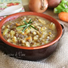 a bowl filled with soup sitting on top of a table next to carrots and potatoes