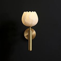 a light that is on the wall next to a black background with a white flower