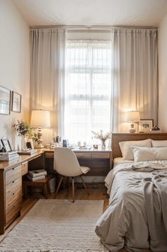 a bedroom with a bed, desk and chair in front of a window that has sheer curtains