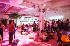 a group of people standing and sitting in a room with pink lighting on the walls