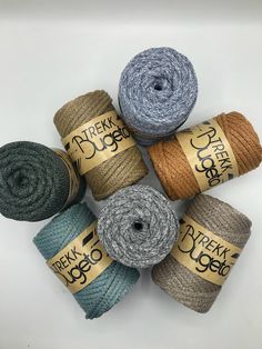 six skeins of yarn in various colors and sizes on a white background with the words derek duge written across each skeins