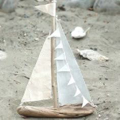 a toy sailboat is sitting on the sand