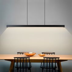 two bowls sit on top of a wooden table in front of a suspended light fixture