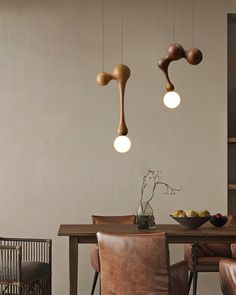 a dining room table with chairs and lights hanging from the ceiling