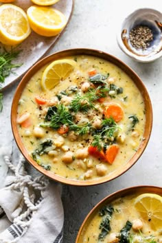 two bowls filled with soup and garnished with lemons, carrots and herbs