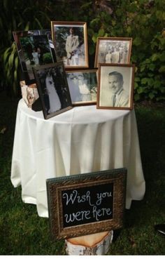 a table topped with pictures and framed photos next to a sign that says wish you were here