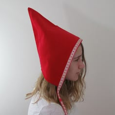 a woman wearing a red hat with white trim on it's head and long blonde hair