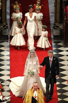 the bride and groom are walking down the aisle with their children in white gowns