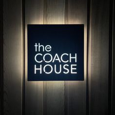 the coach house sign is lit up against a wooden wall