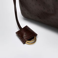 Medium bag by Balenciaga in brown ostrich-effect leather featuring a top handle, a detachable shoulder strap, a removable leather key ring with two open rings, antiqued gold-tone metal hardware, a swivel fastening, a main compartment, an internal zipped pocket, two flat pockets on the back, four press studs on the sides and four brass feet.Width 35 cm x Height 24 cm x Depth 10 cm Shoulder strap length 100 cm Handle drop: 20 cm100% Leather Balenciaga Purse, Leather Key Ring, Balenciaga Handbags, Rings Antique, Open Rings, Medium Sized Bags, Medium Bag, Leather Keyring, Split Rings