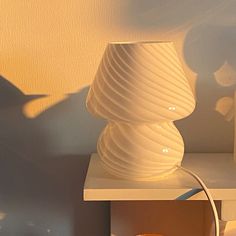 a white lamp sitting on top of a table next to a shelf with a vase