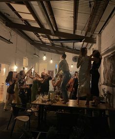 a group of people standing around a table in a room with exposed ceiling and lights