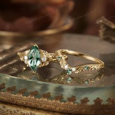 a ring with an oval cut green stone surrounded by small white diamonds on a table