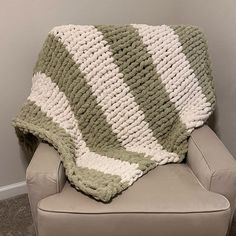 a green and white crocheted blanket sitting on top of a chair next to a wall